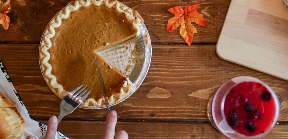 Pumpkin pie being cut and served on a table